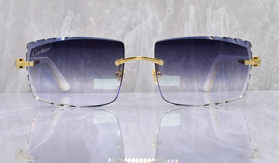 Cartier sunglasses with gold frames and gradient lenses on a reflective surface.