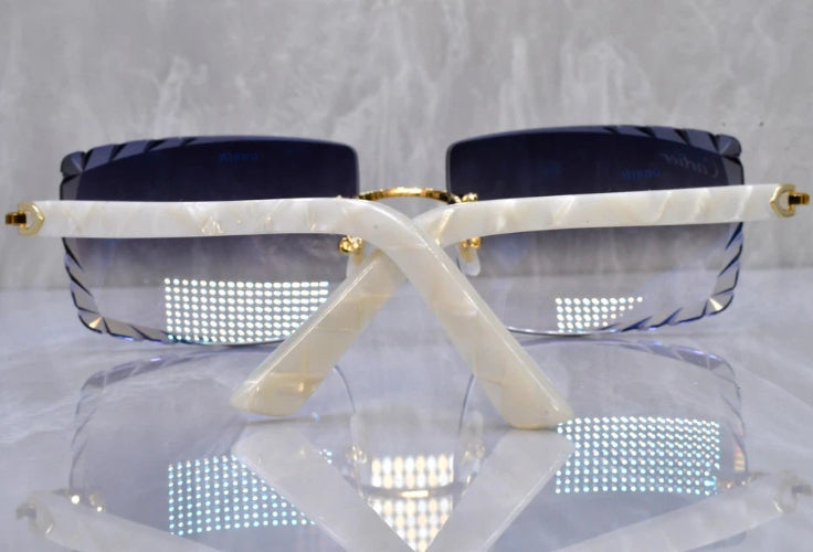 Sunglasses with a white frame and blue lenses on a reflective surface.