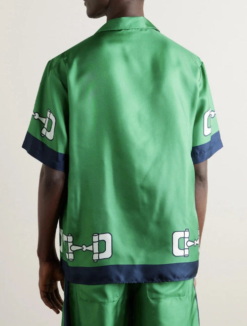 Green satin shirt with brand logos on sleeves and back, worn by a person.