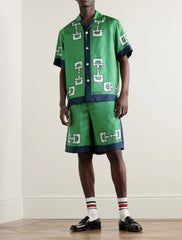 Person wearing a green patterned outfit with matching shoes and socks on a plain background
