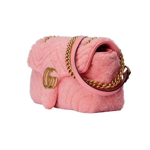 Pink textured handbag with gold chain and logo on a light gray background