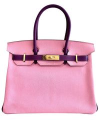 Pink handbag with a black handle on a white background