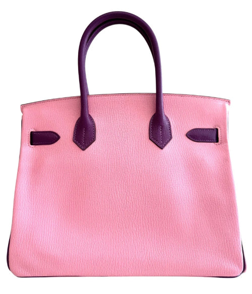 Pink handbag with purple handles and accents on a white background