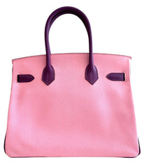 Pink handbag with purple handles and accents on a white background