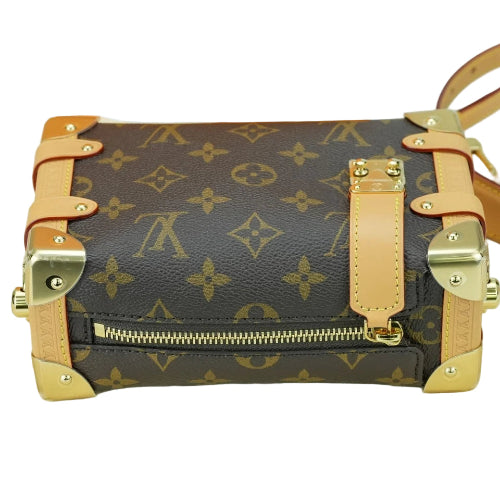 Designer handbag with monogram pattern and gold accents on a white background
