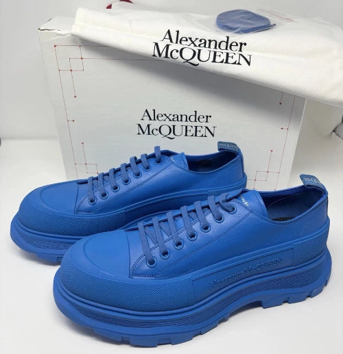 A pair of bright blue low-top sneakers by Alexander McQueen, shown with their white shoebox in the background.