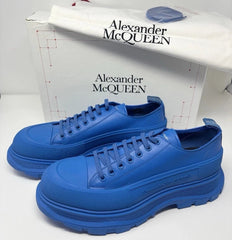 A pair of bright blue low-top sneakers by Alexander McQueen, shown with their white shoebox in the background.