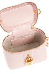 A light pink structured cosmetic bag shown open, featuring gold-tone hardware, a zip-around closure, and a lock detail on the front. The interior is lined in matching pink and light gray fabric.