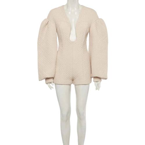 A light beige textured knit romper with dramatic puffed balloon sleeves and a deep plunging neckline, displayed on a white mannequin against a light gray background.