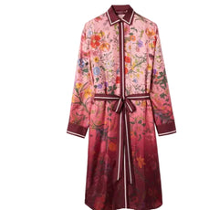 A long-sleeve collared robe with a floral print, featuring a dark red waist tie belt and trim with white piping, shown against a light gray background.