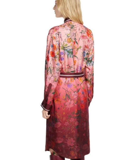 A woman shown from the back wearing a long-sleeve floral robe or kimono-style coat in pink, red, and orange tones with a dark waistband, against a plain white background.