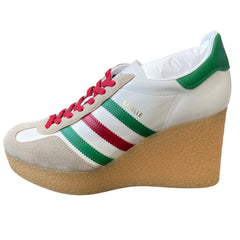 A white platform wedge sneaker with green and red stripes on the side and red laces, shown against a plain white background.