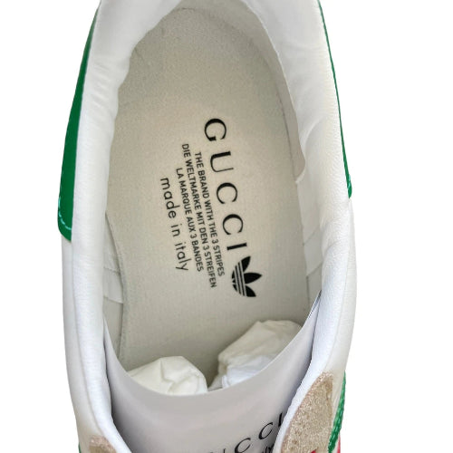 Close-up of the white interior lining of a Gucci sneaker, showing the brand name 'GUCCI' and the green trefoil logo printed on the insole.