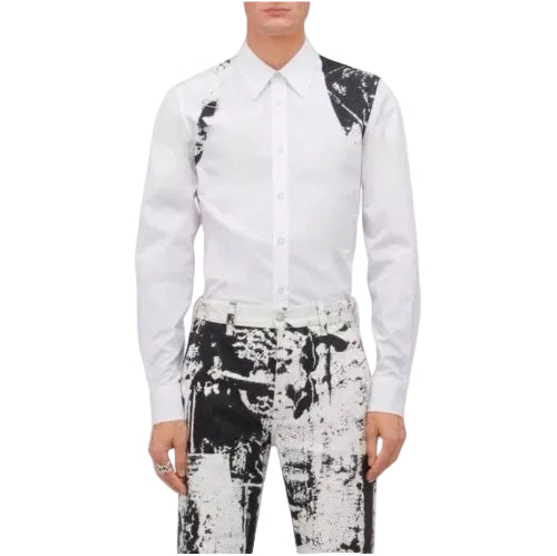 A man wearing a white long-sleeve button-up shirt with black patterned shoulder panels and matching black-and-white patterned trousers, shown against a plain white background.