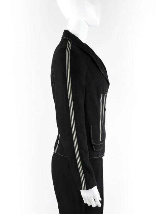 A black tailored jacket displayed on a white mannequin, featuring prominent silver zippers running down the sleeves and on the front pocket.
