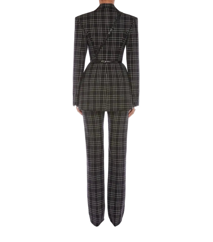 A model shown from the back wearing a matching black and beige plaid blazer and trousers set, featuring structured shoulders, a peplum waist, and straight-leg pants, set against a plain light gray background.