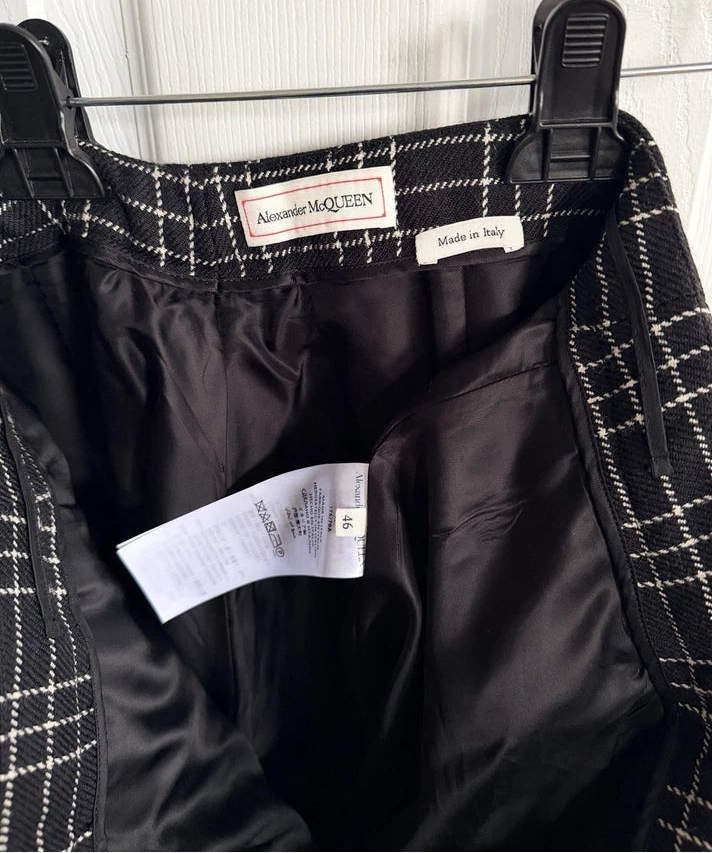 Alexander McQueen black and white plaid skirt shown hanging on a black hanger, displaying the interior lining, waistband, and brand labels.