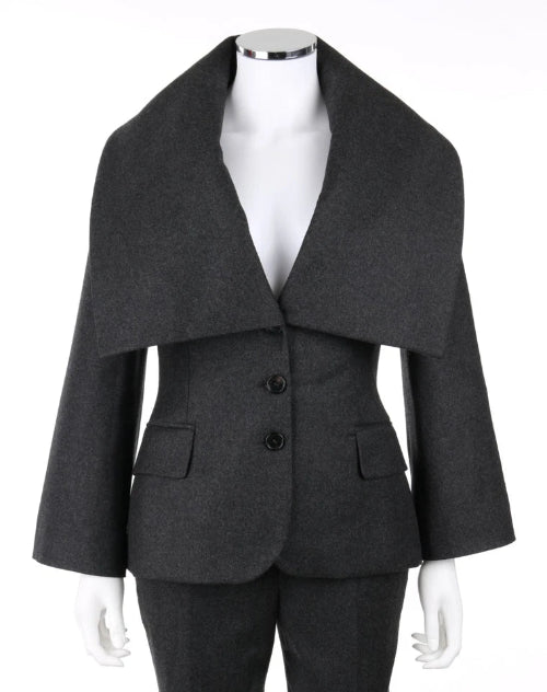 A dark gray wool-blend blazer with a dramatic wide lapel collar, three front buttons, and flap pockets, displayed on a white mannequin torso against a white background.