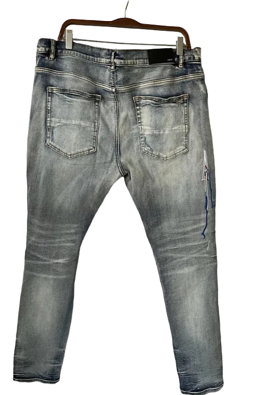 Light wash blue denim jeans shown from the back, hanging on a wooden hanger against a plain white wall.