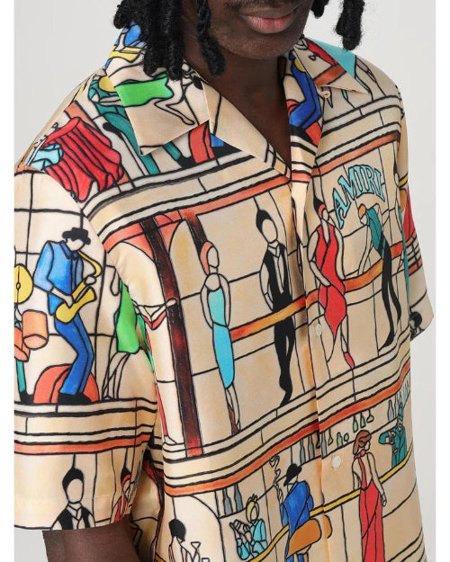 Beige shirt with colorful graphic print of people in a cityscape on a white background
