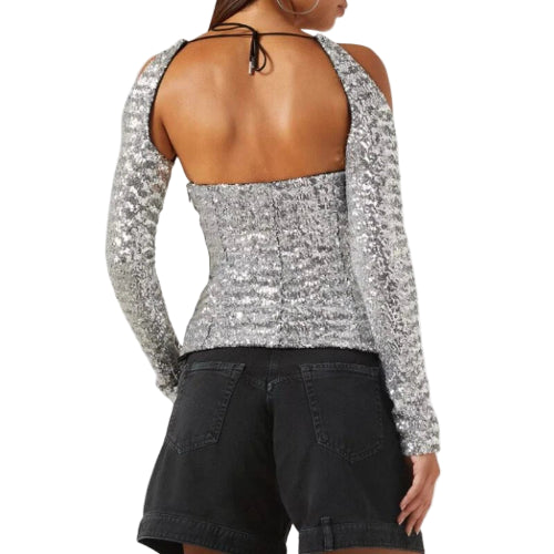 Back view of a person wearing a sparkly silver top and black shorts on a white background
