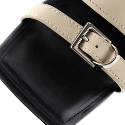 Close-up of a black leather bag with a beige strap and silver buckle on a white background