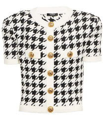 Black and white houndstooth patterned jacket with gold buttons on a white background