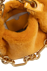 Close-up of a gold-tone chain bag with a plush tan or camel faux-fur texture, showing the chain links and part of the bag's interior.