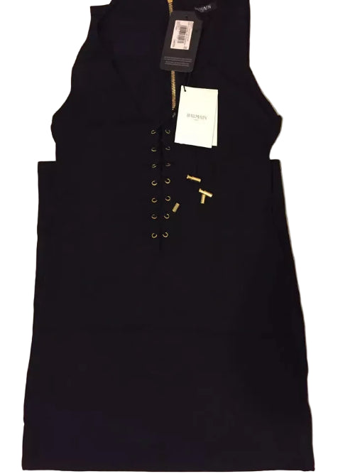 Black sleeveless dress with gold buttons on a textured surface
