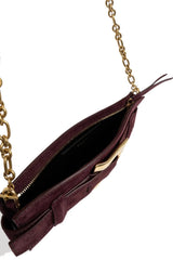 A close-up of a dark plum purple suede crossbody bag with a gold chain strap and gold hardware, shown open against a white background.