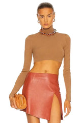 Woman wearing a brown long-sleeve top and red leather skirt on a white background