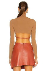 Woman wearing a brown long-sleeve top and red leather skirt on a white background