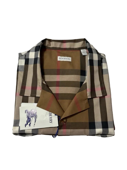 A folded Burberry check shirt jacket in brown, beige, and black, with a brown collar and a white Burberry brand tag visible.