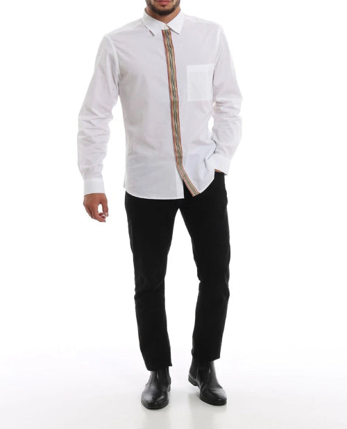 A man wearing a white long-sleeve dress shirt with a unique vertical tie detail, paired with black trousers and black boots, against a plain white background.