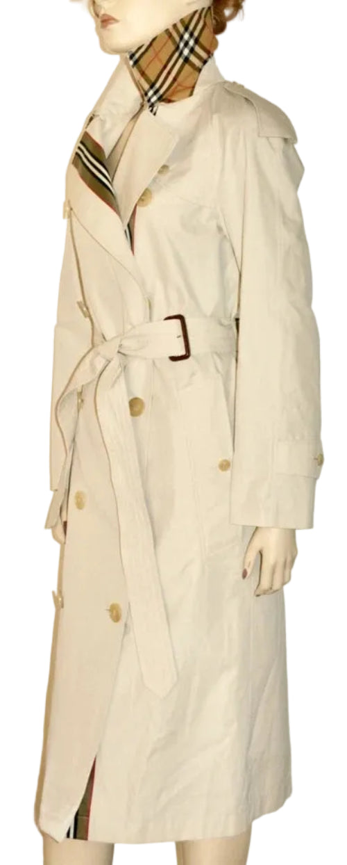 A beige trench coat displayed on a mannequin, featuring a matching beige plaid neck scarf with brown and black stripes.