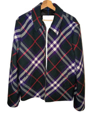A vintage plaid wool jacket hanging on a wooden hanger against a white paneled door. The jacket features a dark green base with a plaid pattern of purple, red, white, and gray.