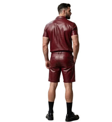 Man wearing a maroon leather outfit standing in a modern indoor setting.