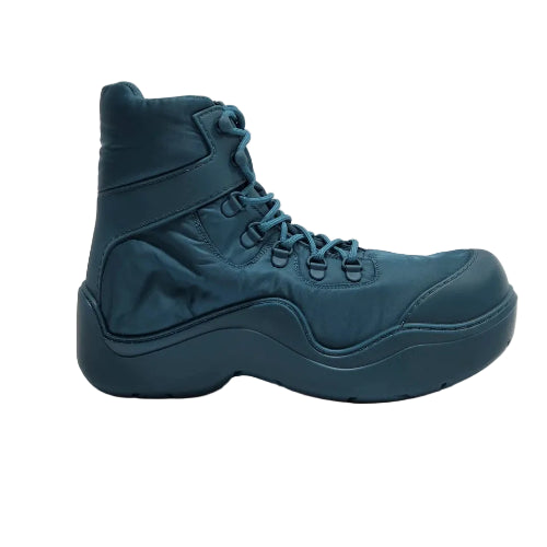 A single high-top sneaker boot in a deep teal blue color, featuring a thick sculpted sole and matching laces, photographed against a neutral light gray background.