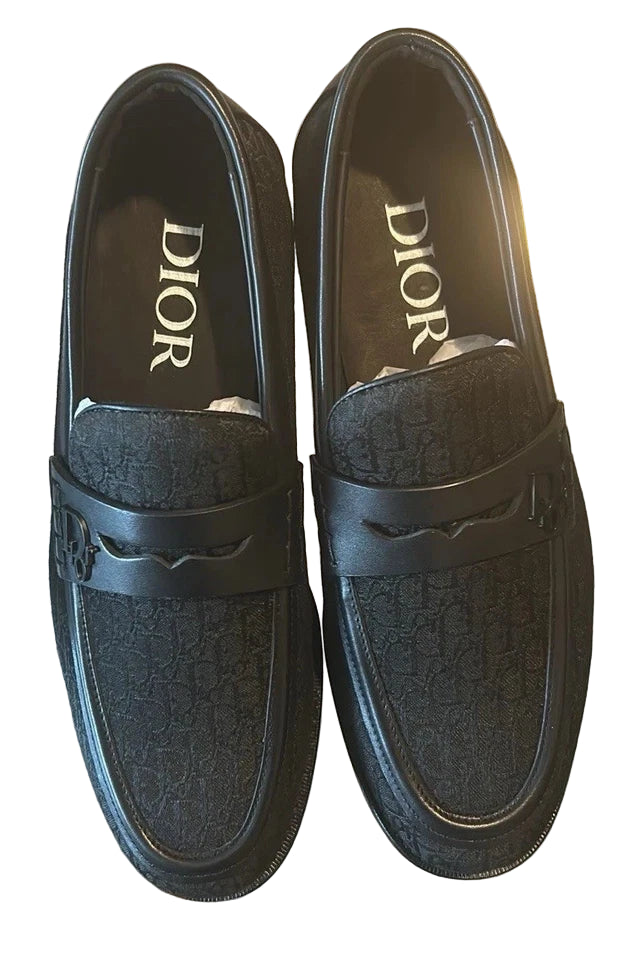 Pair of black Dior loafers on a reflective surface