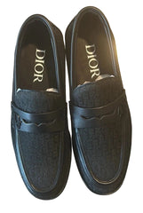 Pair of black Dior loafers on a reflective surface
