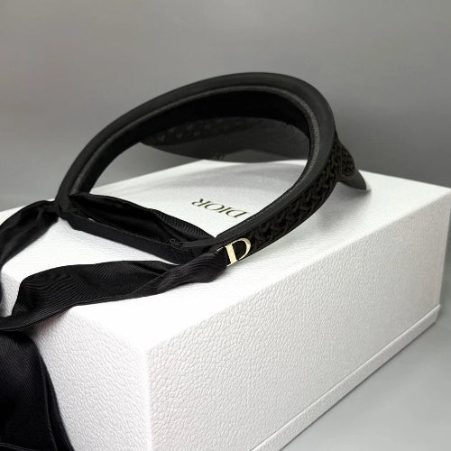 A black leather strap, likely a camera strap or belt, draped over a white rectangular box on a light gray background.