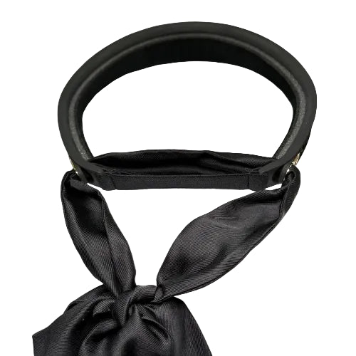 A black Dior visor hat with a matching black satin ribbon bow, displayed on a white textured box with the Dior logo visible inside the visor.
