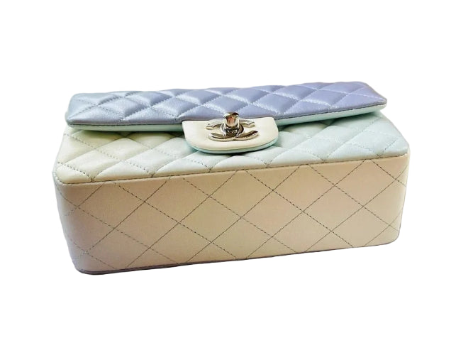 Quilted handbag with a light blue flap on a textured surface