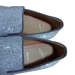 Pair of blue loafers with 'Paris' and 'Christian Louboutin' branding on a wooden surface.