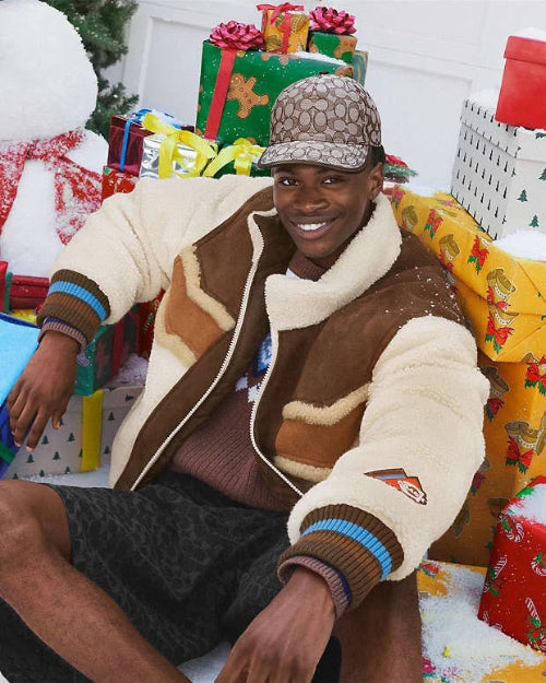 Person wearing a brown and beige jacket with a patterned cap, surrounded by Christmas presents and decorations.