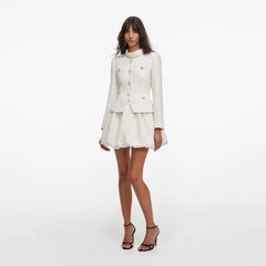 Woman wearing a white outfit with a jacket and skirt on a white background