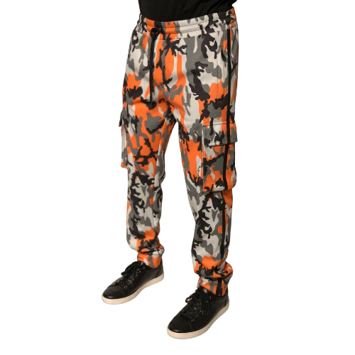 Camouflage pants with orange and gray pattern worn by a person on a white background