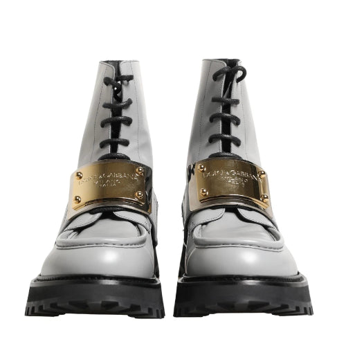 A pair of white lace-up combat boots with gold metal accents and black soles, shown against a plain white background.
