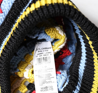 Close-up of a knitted textile product showing a white product tag with the brand name 'ACE GABBANA' and color details. The fabric features a striped pattern of black, yellow, light blue, white, and red yarn.