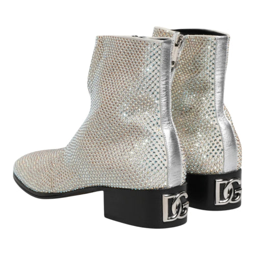A pair of women's ankle boots with a textured silver snakeskin pattern, featuring a low black block heel and a silver buckle detail on the side.